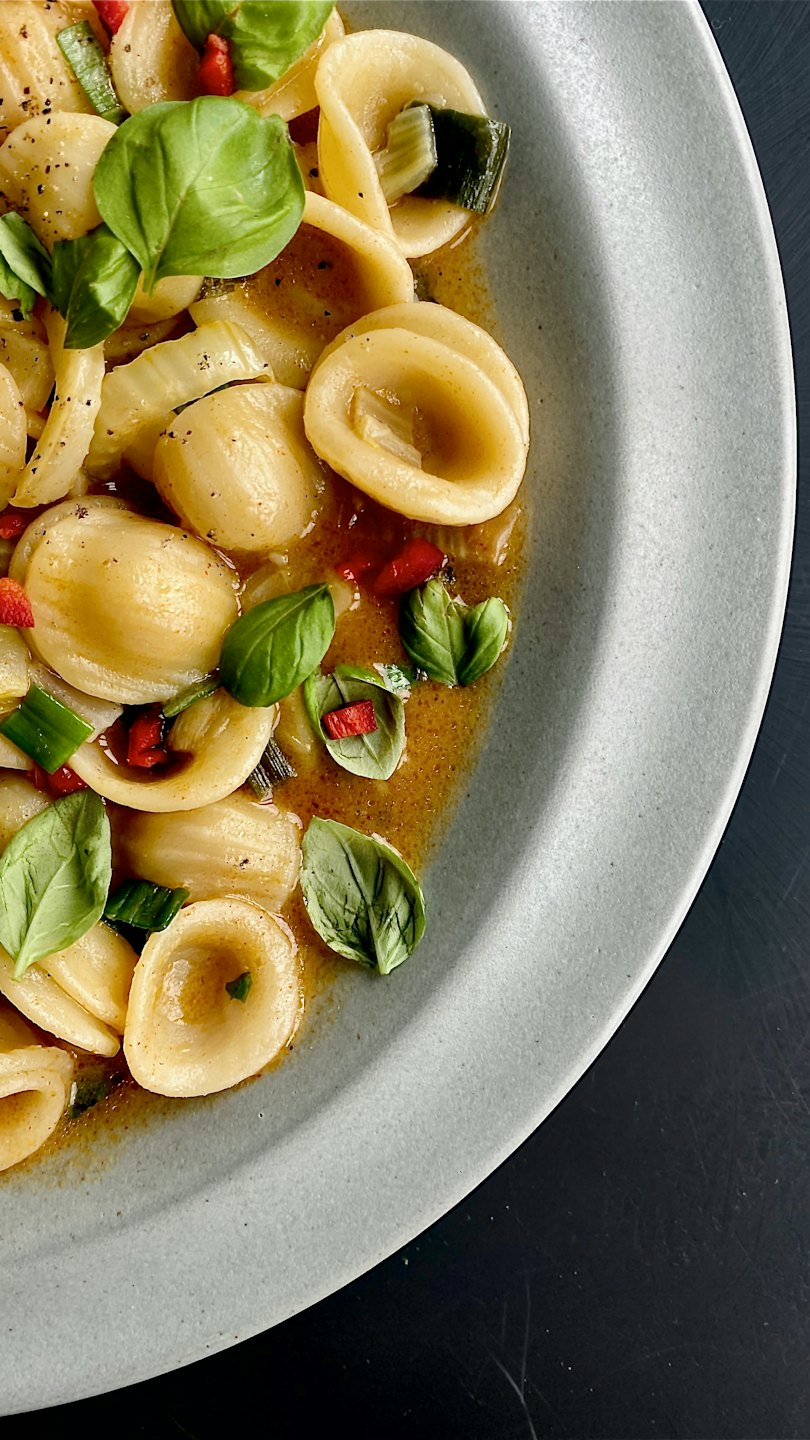 Orecchiette con erbe fresche e peperoni su un piatto.
